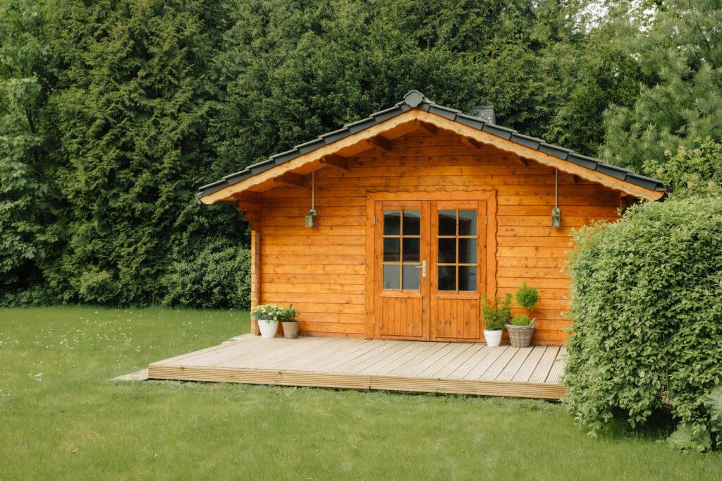 Eine charmante Holz-Gartenhütte in einem gepflegten Garten bietet zusätzlichen Stauraum und Platz für Mülltonnenbox 2er, um den Außenbereich ordentlich zu halten.