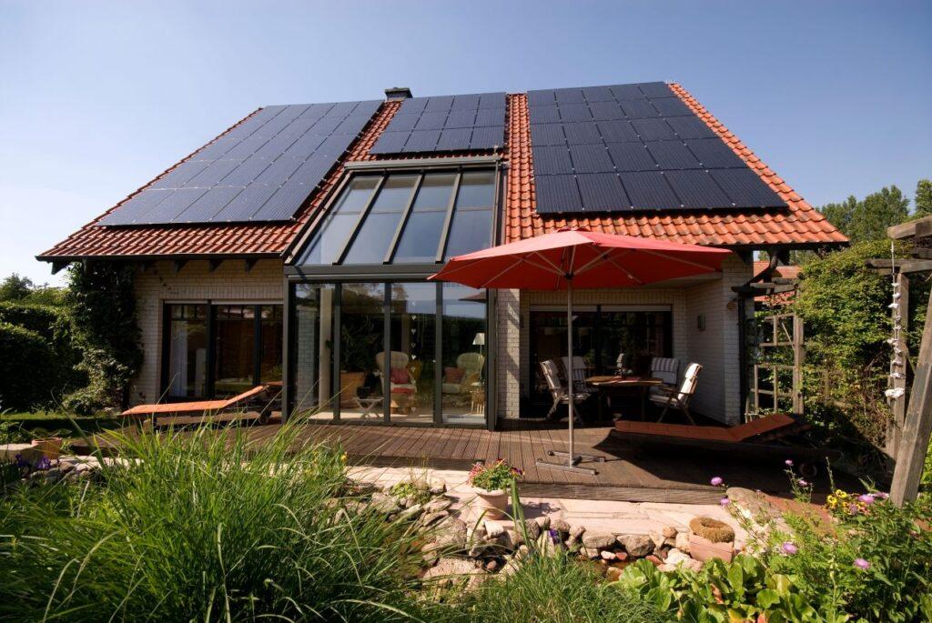 Haus mit großen Solarmodulen auf dem Dach, umgeben von einem gepflegten Garten, nachhaltige Lösung durch PV Anlage Halle.