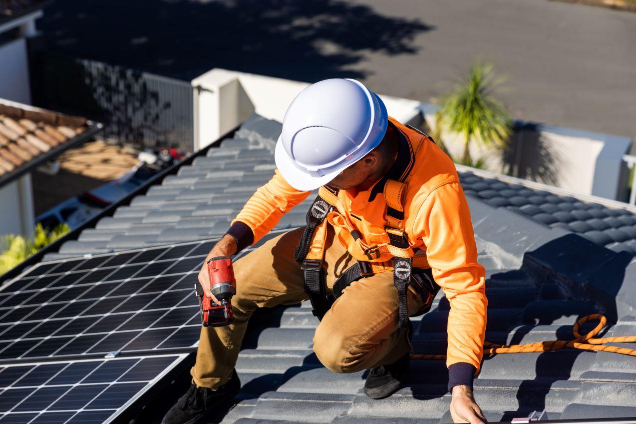 Monteur mit Schutzkleidung bei der Installation von Solarpanels auf einem Dach in Halle, nachhaltige Energie durch PV Anlage Halle.